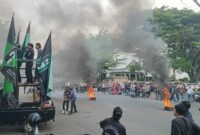 Massa HMI membakar ban saat menggelar aksi unjuk rasa di depan Polrestabes Makassar, Senin (5/5), menuntut pencopotan Kapolrestabes dan Kasatreskrim atas pembubaran lapak baca.