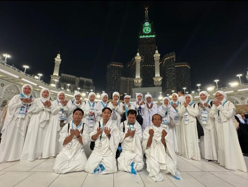 Jamaah umrah ZZ Travel berdoa bersama di pelataran Masjidil Haram, Makkah, dengan latar Menara Abraj Al Bait, mencerminkan kekhusyukan dan kebersamaan dalam ibadah.